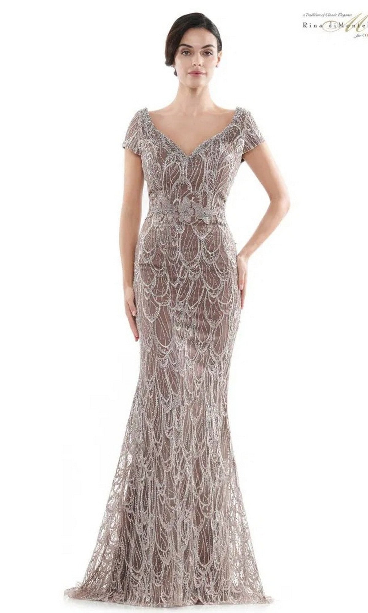 A woman in a coffee-colored, floor-length Rina Di Montella RD2716 gown featuring short sleeves and ornate, draped beadwork.